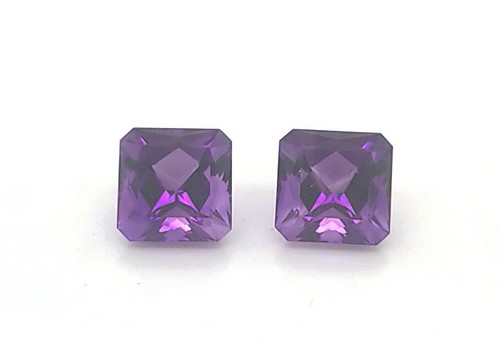 Two Gem Stones in Violet Placed on a White Background